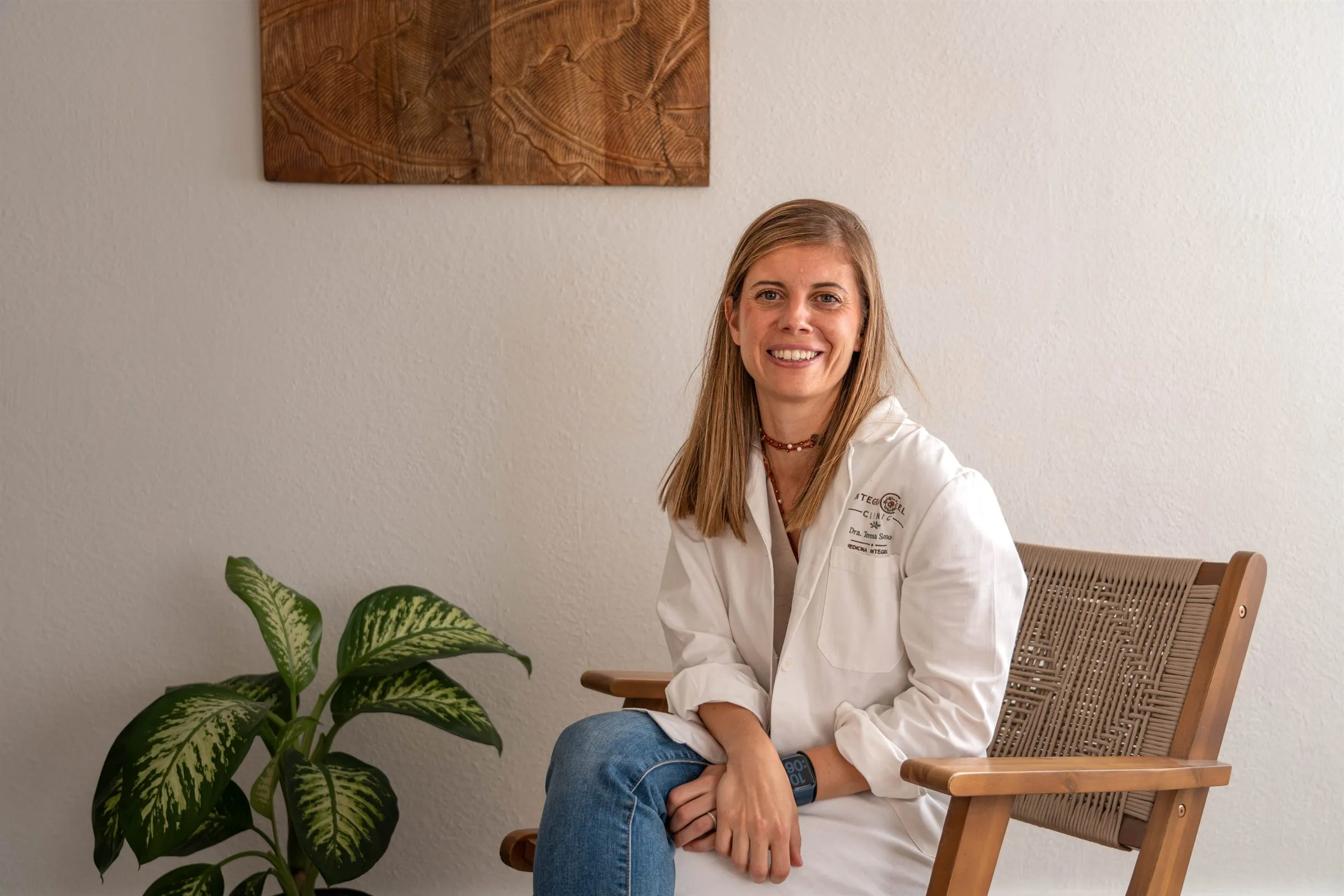 La Dra. Teresa Soriano sentada en una butaca de madera en la consulta de Integracel Clinic